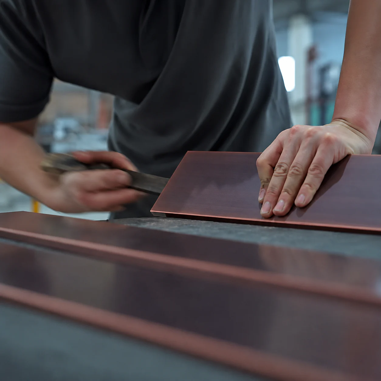 An artisan refining the edge of a copper panel
