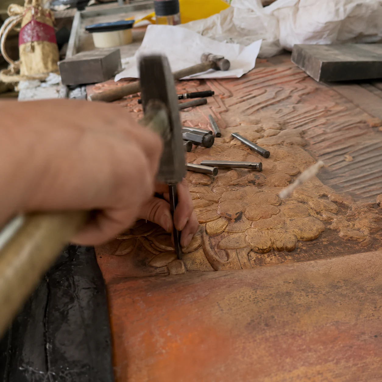 A floral copper relief being carved by hand